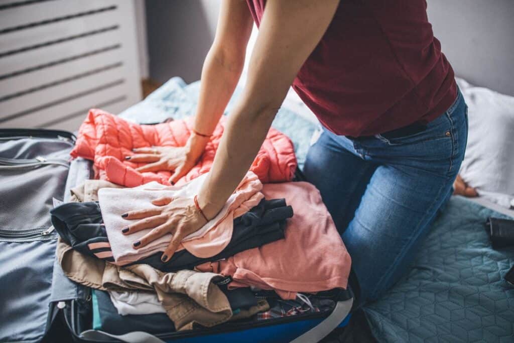 A woman pressing clothes into her suitcase on the bed
@canvapackingsuitcase