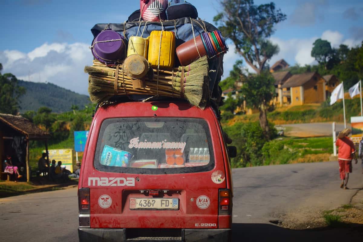 An overloaded mini bus in Madagascar, with bags and luggage pile high and tied down on top. @depositphoto (https://depositphotos.com/editorial/madagascar-61887635.html)