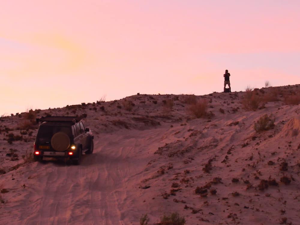 man and jeep on hill in the Namibia Sunset