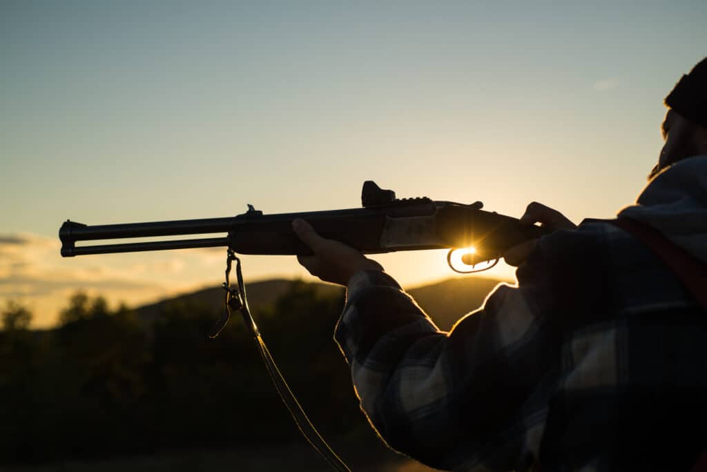 Barrel of a gun. Rifle Hunter Silhouetted in Sunset.