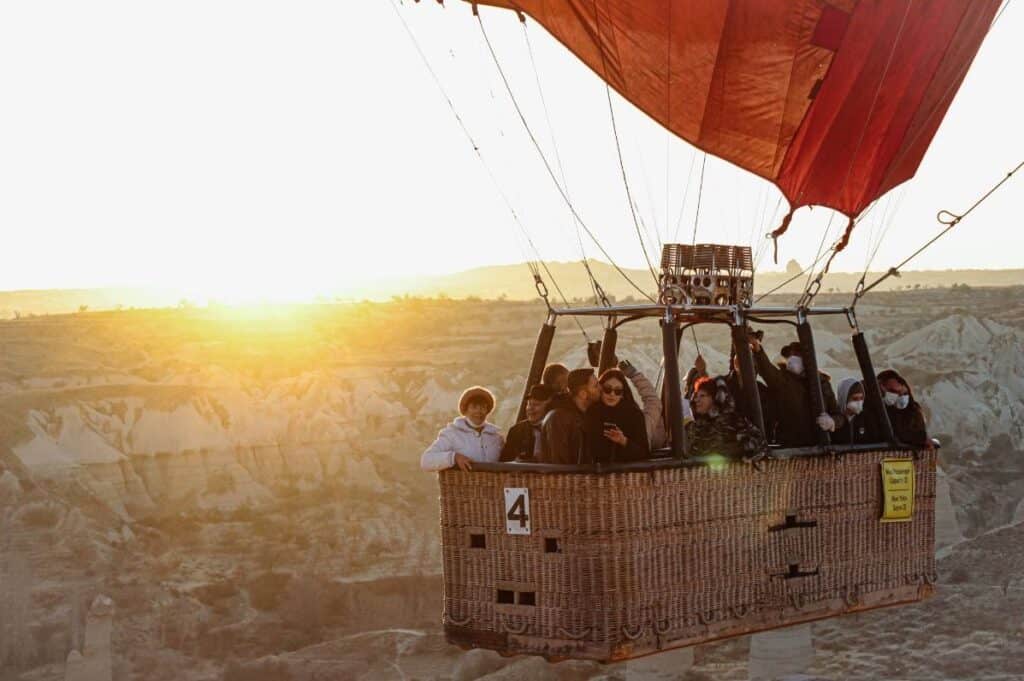 Hot air balloon in flight, the large basket full of people.