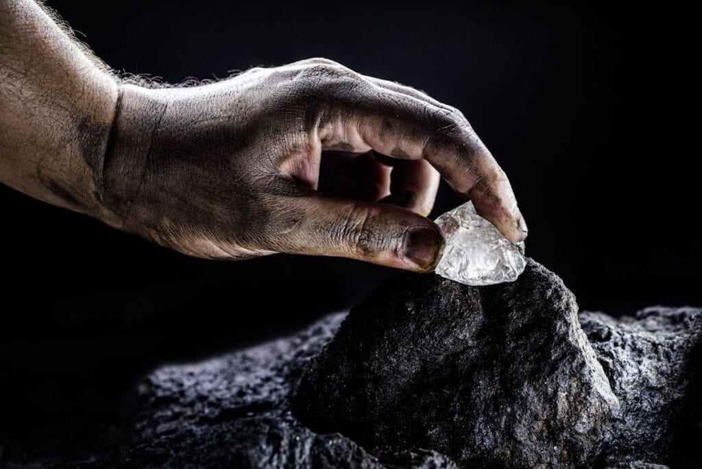 A hand holding a large diaming against a dark background