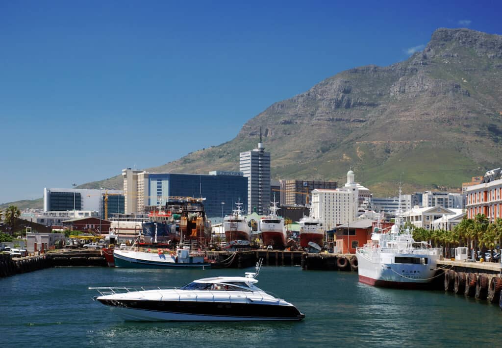 Photo of the V&A Waterfront from the water - buildings with the side of Table Mountain in the background.
