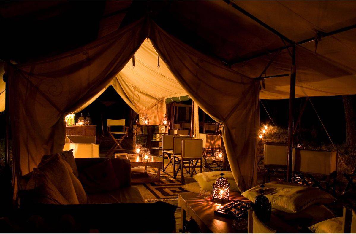 A luxury safari tent in Tanzania, at night, lit by candles.