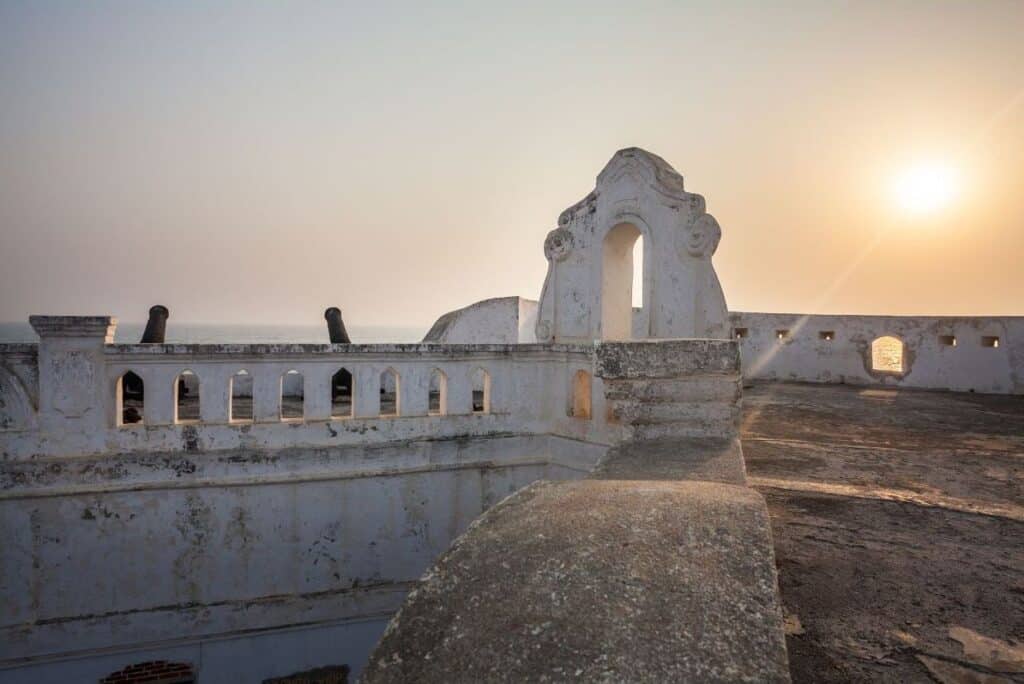 Cape Coast Castle, Ghana, against a clear gold sky at sunset