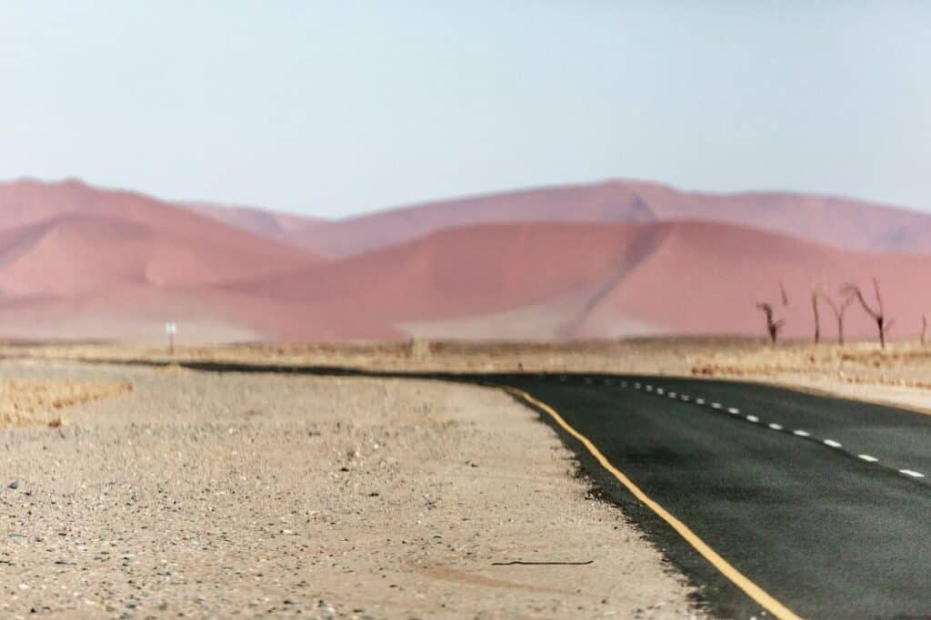 A less-travelled nicely-paved road in Namibia, a top place to travel, passing beautiful red sand dunes.